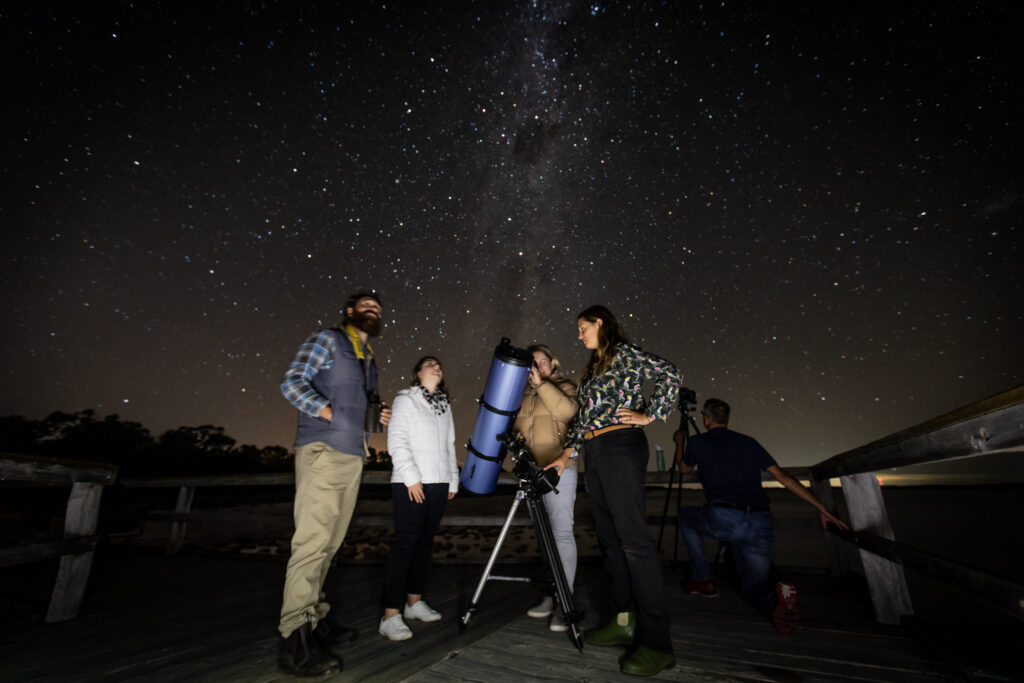 4 peiople star gazing with a telescope