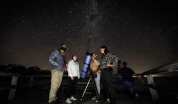 4 peiople star gazing with a telescope